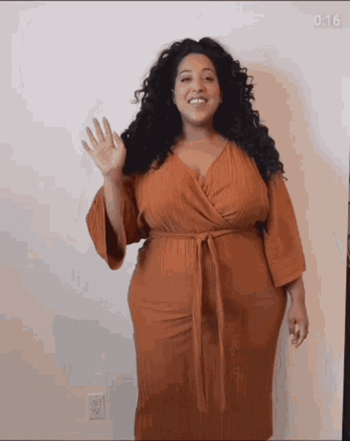 a woman with curly hair is wearing a brown dress