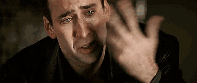 a man with tears running down his face is making a funny face with his hand .