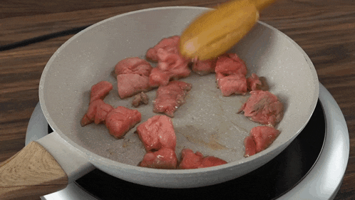meat is being cooked in a pan on a stove