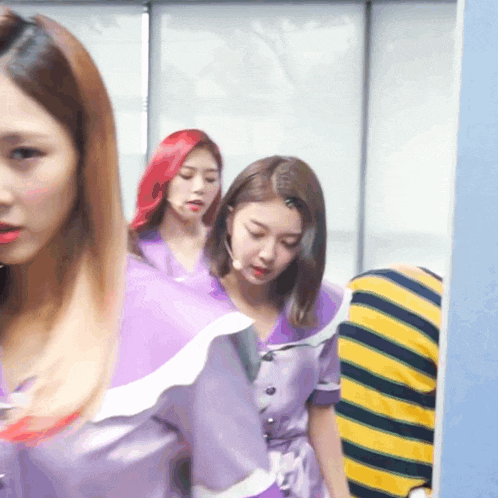 a woman with red hair is standing next to two other women in purple dresses