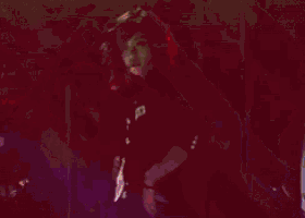 a woman in a black jacket is waving her hand in the air
