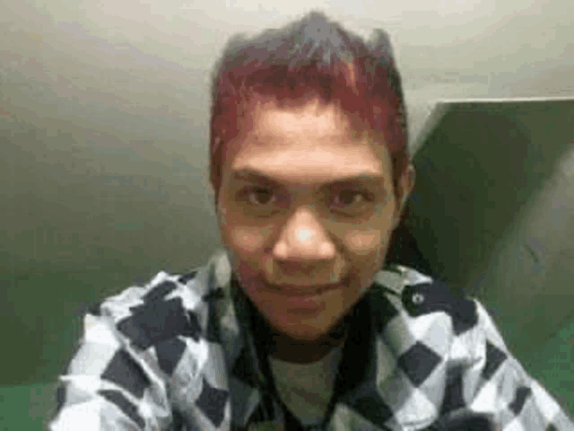 a young man with red hair is taking a selfie with his phone .