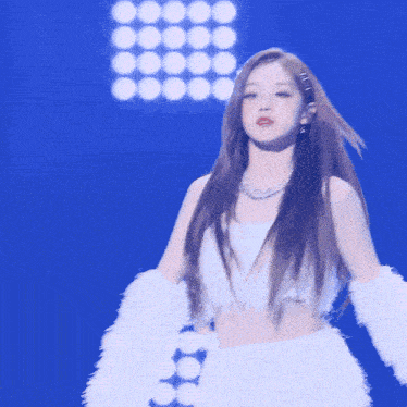 a woman singing into a microphone while wearing a white fur coat