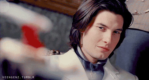 a man with long hair is wearing a white suit and a bow tie .