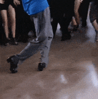 a man in a blue shirt is dancing in front of a group of people