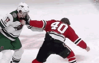 two hockey players are fighting on the ice and one of them has the number 40 on his back .
