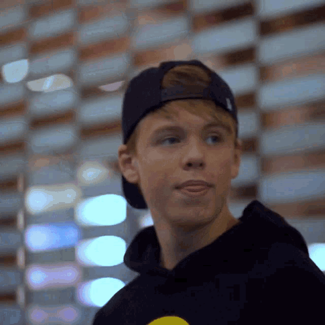 a young man wearing a hat and a black hoodie
