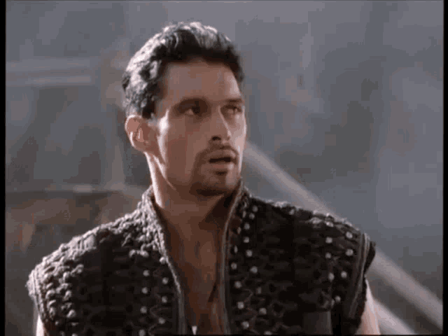 a man with a beard wearing a black vest with studs