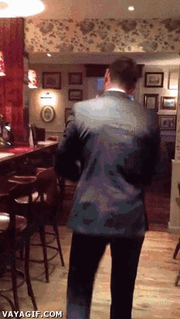 a man in a suit is walking through a restaurant with a vayagif.com watermark