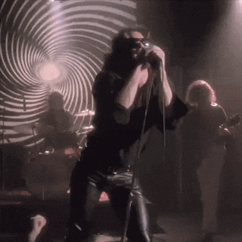 a man singing into a microphone in front of a swirl background