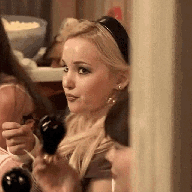a woman is holding a microphone in her hand and looking at herself in a mirror .