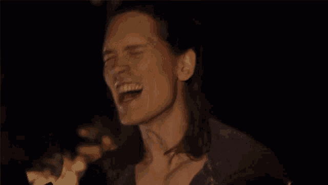 a man with long hair is screaming with his mouth open