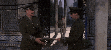three men in military uniforms stand in front of a doorway