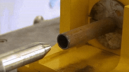 a metal pipe is being drilled into a yellow object