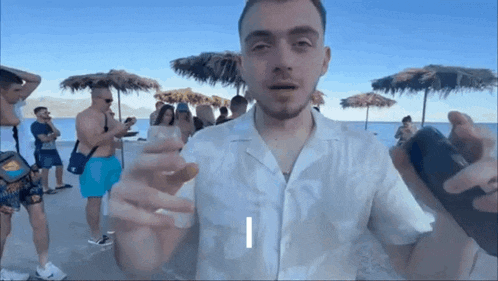 a man is standing on a beach holding something in his hand with the letter i visible