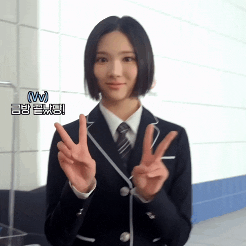 a girl in a school uniform is giving the peace sign