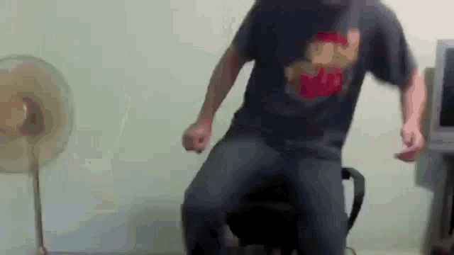 a man wearing a shirt that says mario is dancing in front of a fan