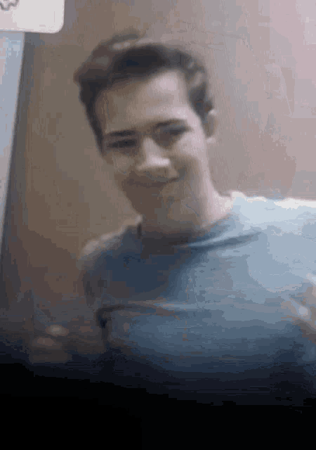 a man in a blue shirt is smiling and looking at the camera .