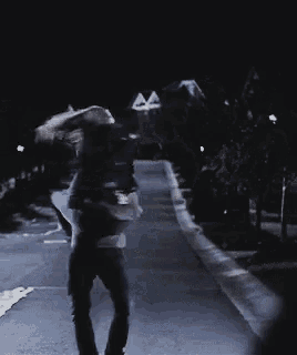 a person walking down a street at night with a building in the background