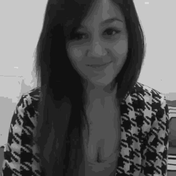 a black and white photo of a woman wearing a houndstooth jacket and a bra .