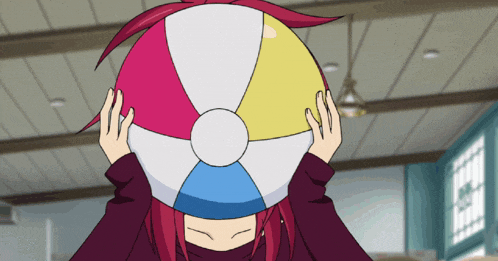 a girl with red hair is holding a beach ball over her face