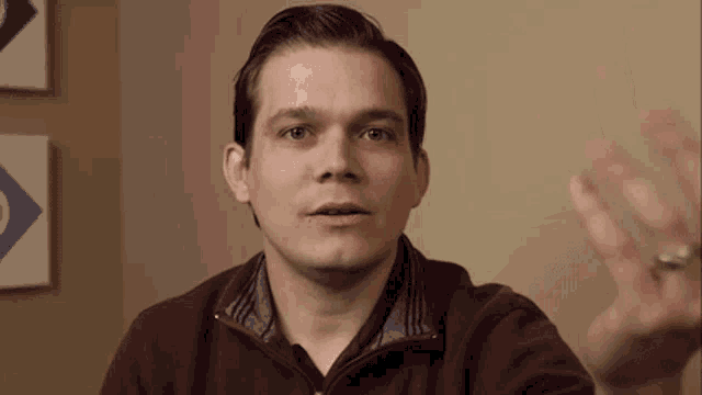 a man in a maroon sweater is making a face