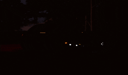 a car is parked in the dark with its headlights on