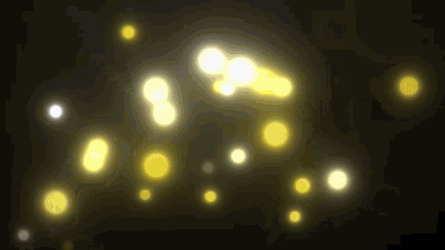a bunch of yellow lights are flying in the air on a black background