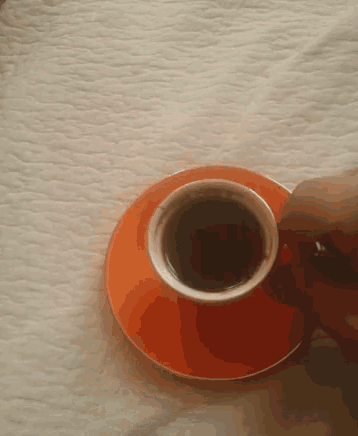 a cup of coffee is on an orange saucer on a table