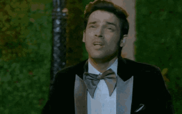 a man in a tuxedo is holding his hands up in the air