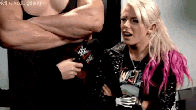 a woman with pink hair is sitting next to a man with a microphone .