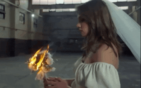 a woman in a wedding dress is holding a burning flower in her hands .