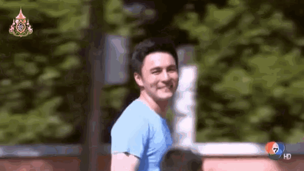 a man in a blue shirt is smiling while walking down the street .