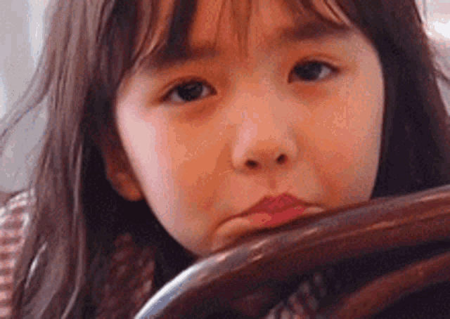 a little girl is sitting in a chair looking at the camera .