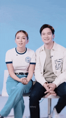 a man and a woman are sitting next to each other with a blue background
