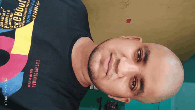 a man with a shaved head wears a black shirt that says ' exclusive ' on the front