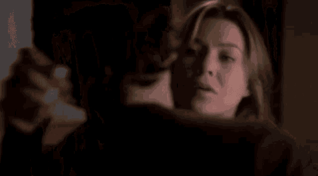 a man is holding a woman in his arms in a dark room in a close up .