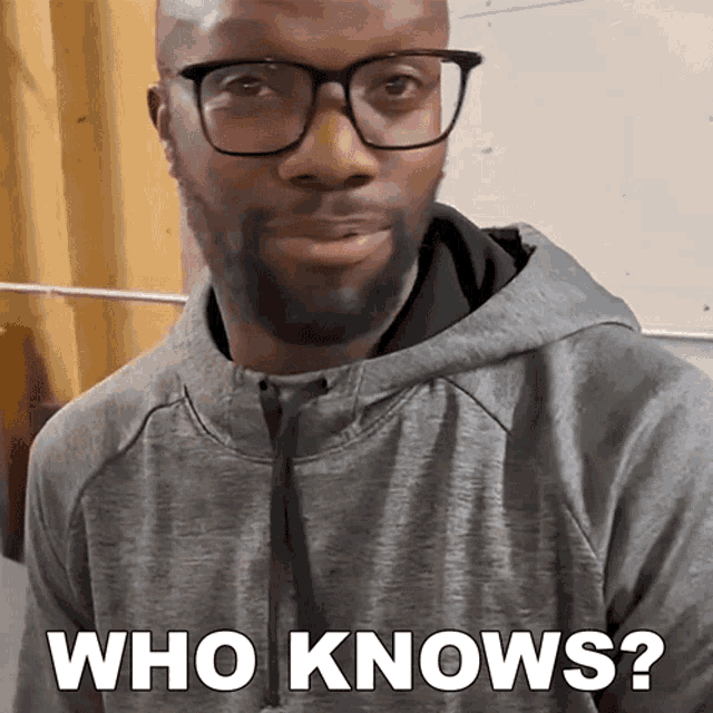 a man wearing glasses and a grey hoodie is asking who knows