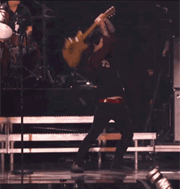 a man playing a guitar in front of a fender cabinet