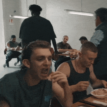 a man in a tank top with the letter w on it is eating