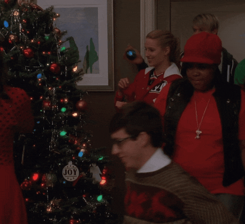a christmas tree with a joy ornament hanging from it