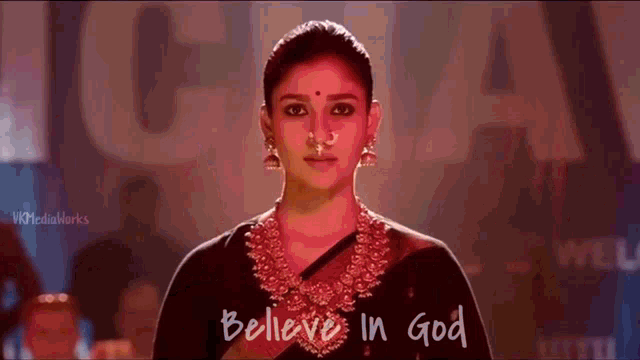 a woman with a nose ring stands in front of a sign that says " believe in god "