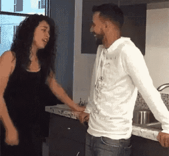 a man and woman are holding hands in a kitchen .
