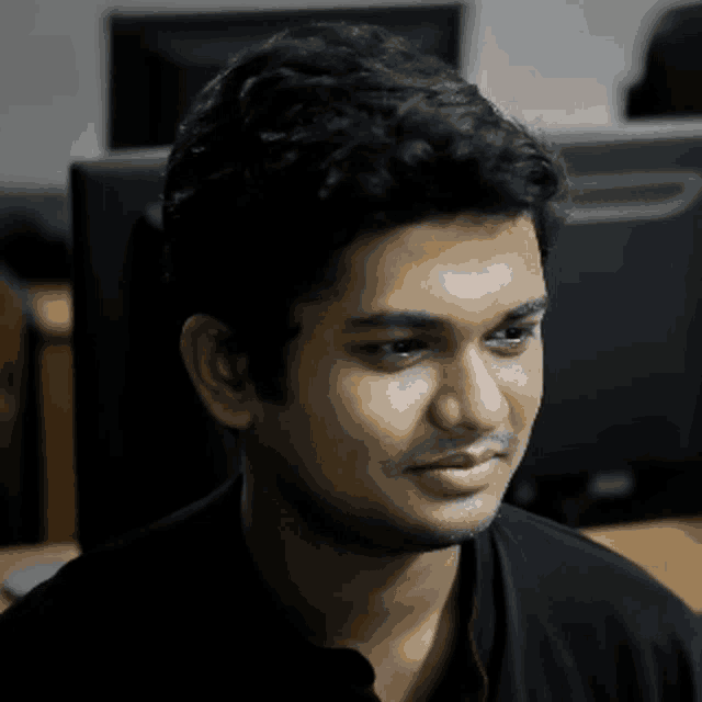 a man in a black shirt is sitting in front of a computer