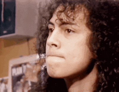 a close up of a person 's face with curly hair looking at something .