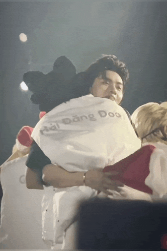 a man wearing a shirt that says dong doo is hugging another person