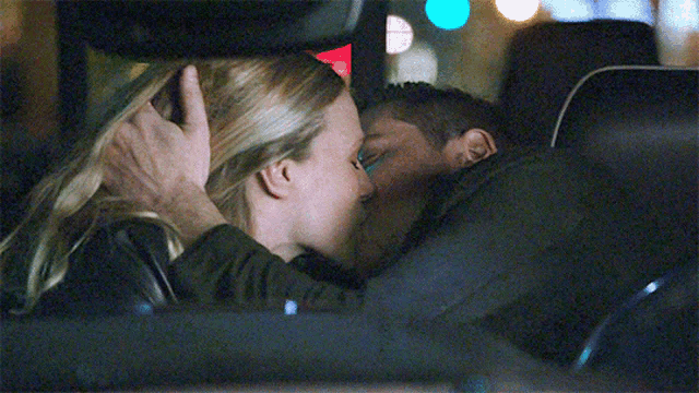 a man and a woman are kissing in the back seat of a car at night .
