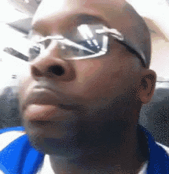 a man wearing glasses and a blue shirt is looking up