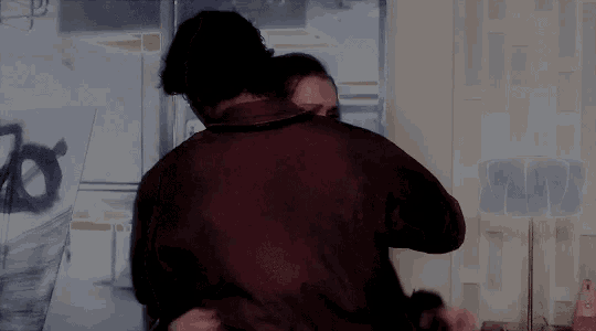 a man and a woman are hugging each other in front of a wall with the letter o painted on it