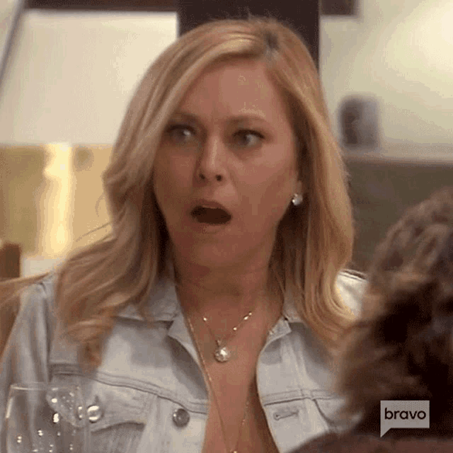 a woman is making a surprised face while sitting at a table .